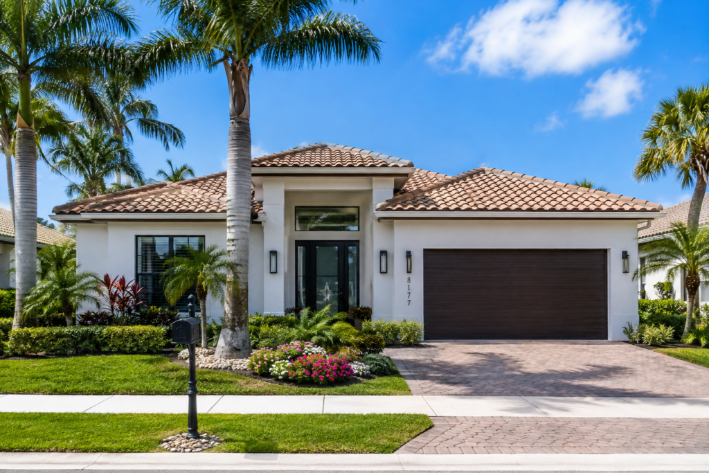 A Florida single-family home with a tile roof, palm trees and a paver driveway